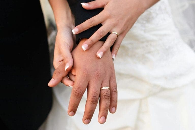 Engagement ring and wedding band stacked together on a hand in soft natural light