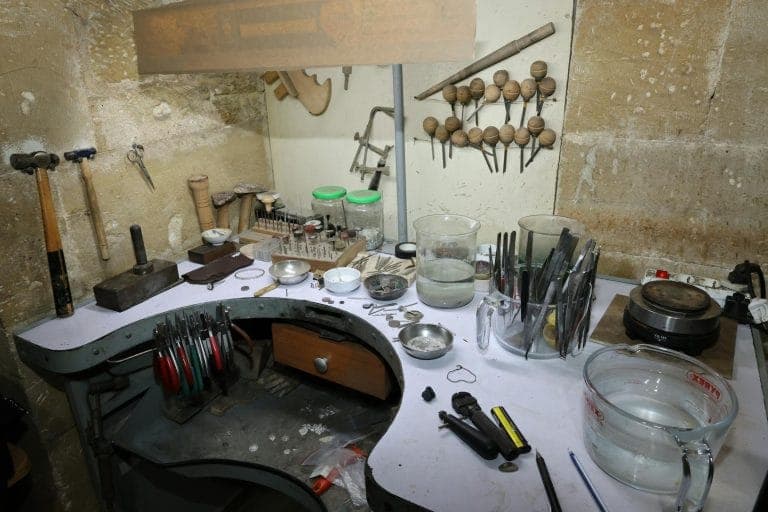 Small jewellery studio workspace with tools, finished pieces and a laptop