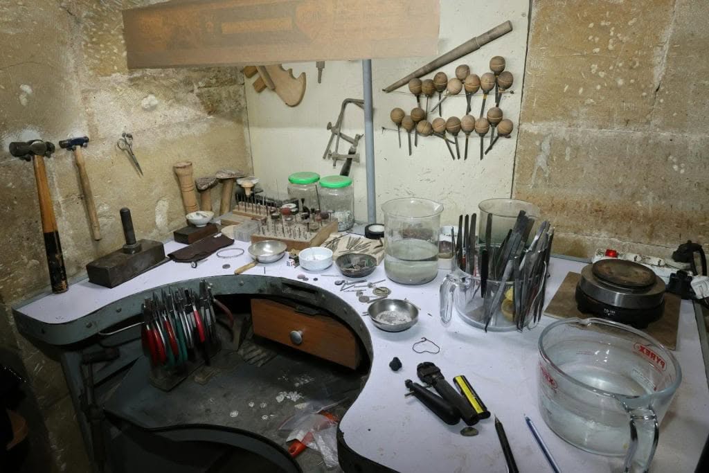 Small jewellery studio workspace with tools, finished pieces and a laptop